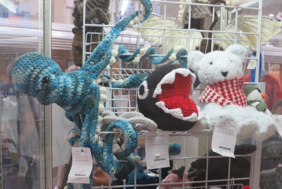 white metal shelf with knitted octopus, knitted Chain Chomp, and white teddy bear.