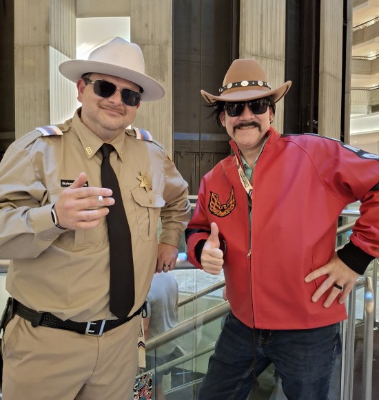 Smokey and the Bandit costumes, leaning near elevator banks.