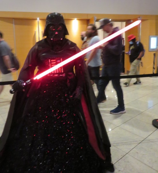 Darth Vader costume in darkness with red lightsaber, but in glittering robe.