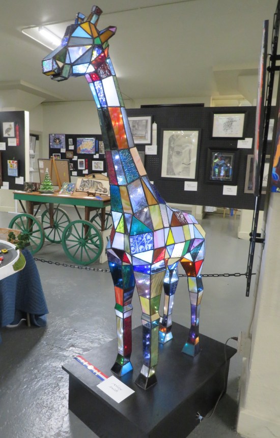 a stained glass giraffe taller than me in an art gallery.