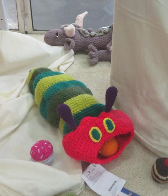 knitted doll of the Very Hungry Caterpillar in a display case