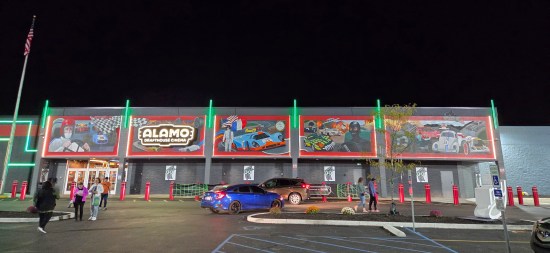 Alamo Drafthouse Indy at night with racing-movie murals above the doors and windows.