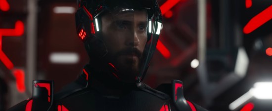 Jared Leto in black and red CGI armor. The glass faceplate retracted partially to reveal his face. Everything around him is red lines.