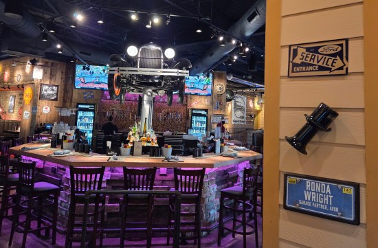 antique auto up on a hydraulic jack inside a restaurant bar.