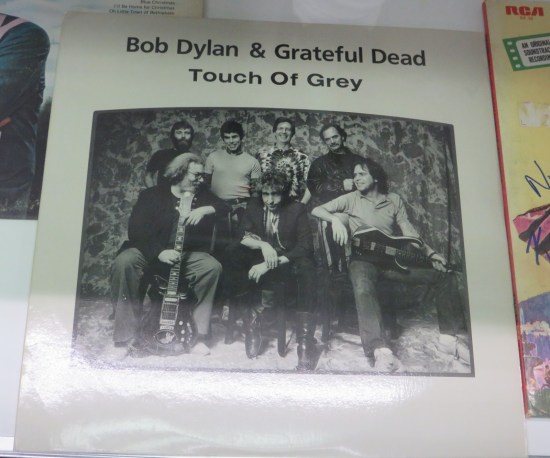 Record cover of Bob Dylan and the Grateful Dead called "Touch of Grey" with black and white photo of them.