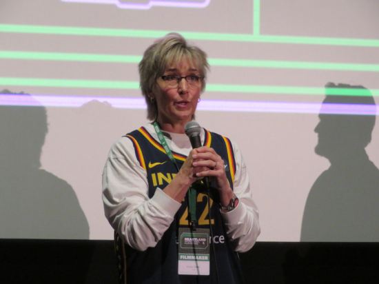 Christy Salters with mic in front of a movie screen, answering a question.