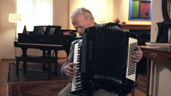 Frank Grunwald sitting with eyes closed while playing the accordion.