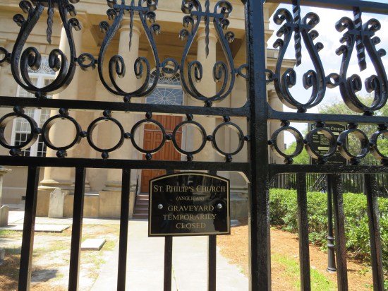 Locked gate to a church and cemetery, sign says "Graveyard Temporarily Closed"