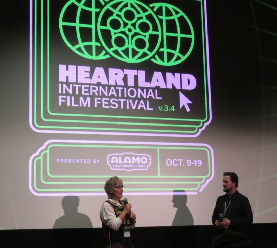 Wide shot of Christy Salters and Greg Sorvig in front of screen with green-on-black HIFF logo, Alamo Drafthouse logo, and festival dates of October 9-19.