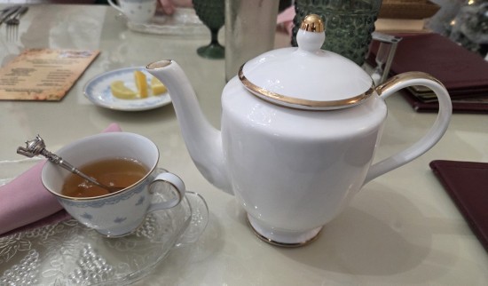 White teapot and teacup on a white restaurant tablecloth.