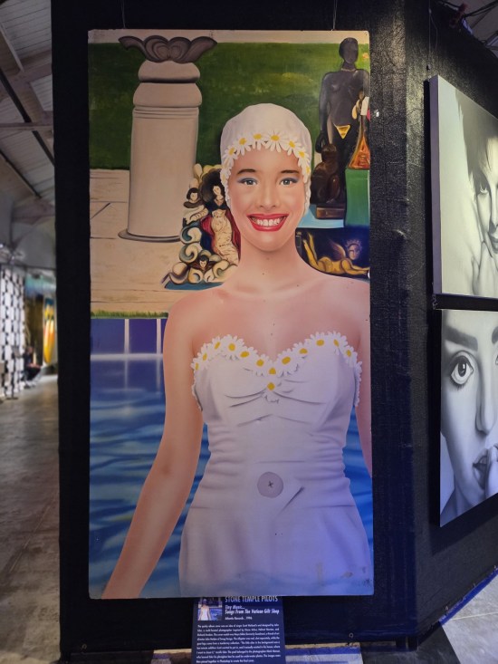 Large painting of a weirdly happy woman in one-piece 20th-century swimsuit and yellow swimming cap.