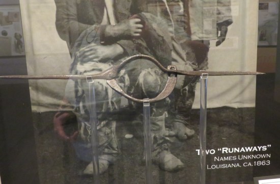 A metal slave yoke in front of a 19th-century photo of a Black couple posing.