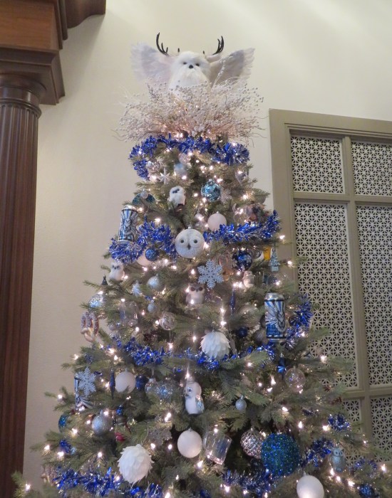 White tree with blue garland, white owl ornaments, and cans of Blind Owl alcohol.