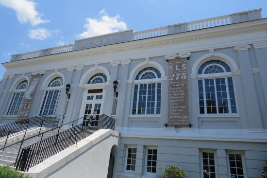 Large two-story white building with arches above all the second-story windows.