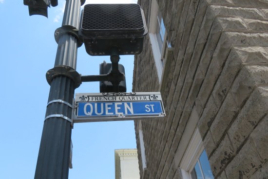 Blue Queen Street sign above us in a white French Quarter frame.