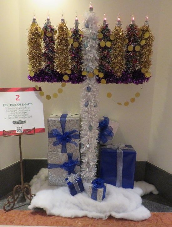 Hanukkah menorah about the same size and piney texture as a Christmas tree, tucked into a hallway alcove.