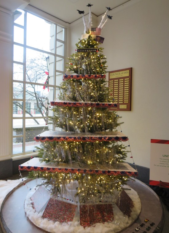 Christmas tree stratified into a five-floor pagoda. Toppers are tiny Blue Angels planes flying away in trails of smoke.