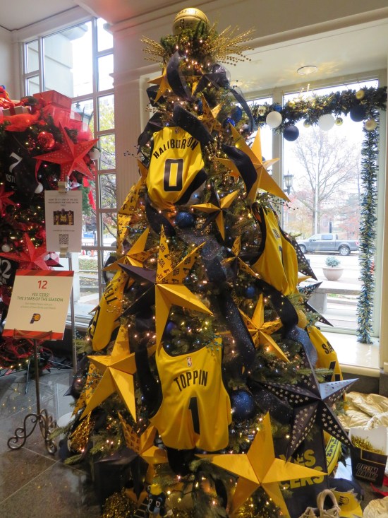 Christmas tree with large yellow stars and Pacers uniforms tossed all over it.