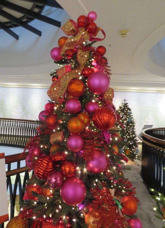 Christmas tree covered in lots of big red and orange ball ornaments.