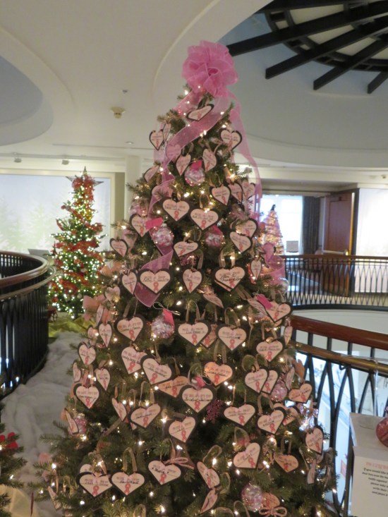 Christmas tree almost completely covered in pink hearts with breast cancer victim names written on them by loved ones.