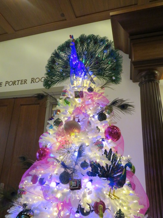 White tree with wispy pink ribbons and multiple peacocks, including a big topper.