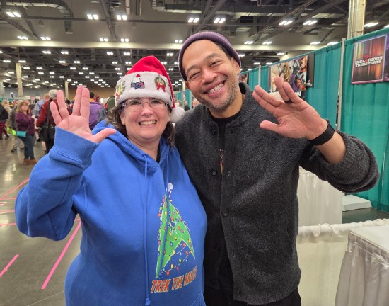 Eugene Cordero and Anne in her Santa hat, both doing Vulcan hand-signs.