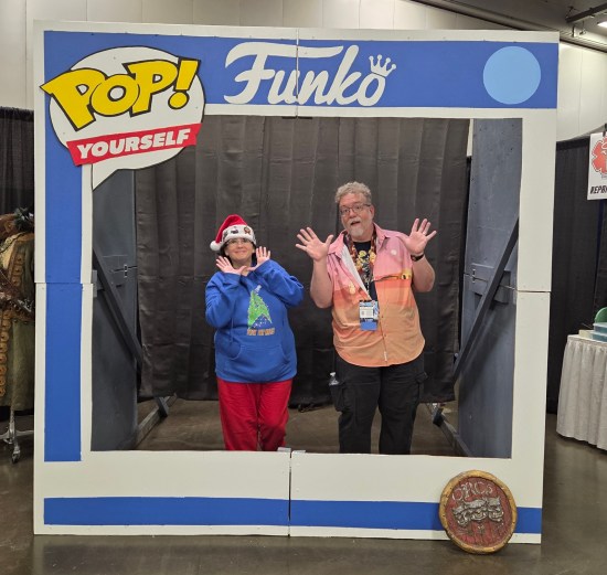 Us doing jazz hands in a giant Funko Pop box. Anne is wearing a Santa hat and Christmas-themed Trek hoodie.