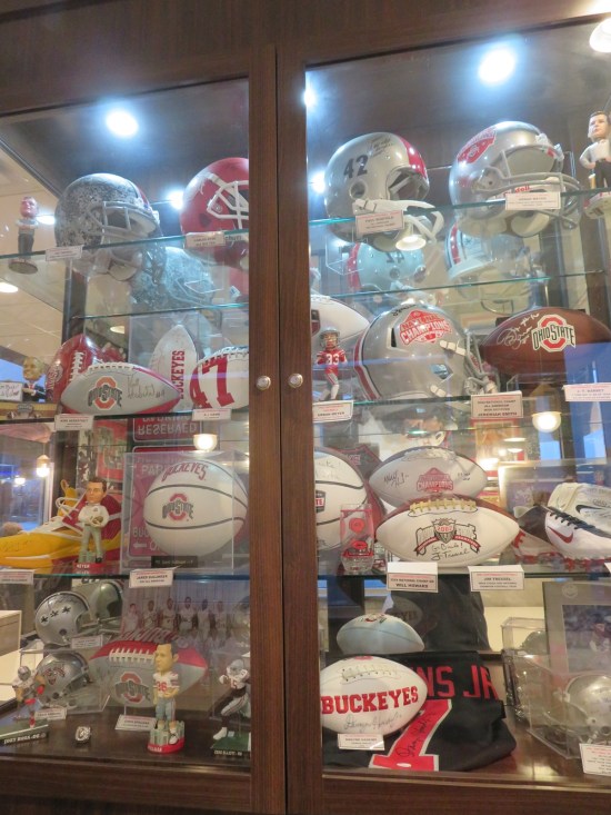 OSU helmets and footballs in a vitrine standing from floor to ceiling.