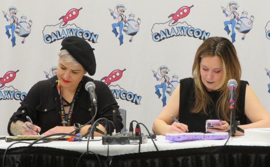 Hutchison and Kangas share a panel table, each with drawing implements and sketchbooks.