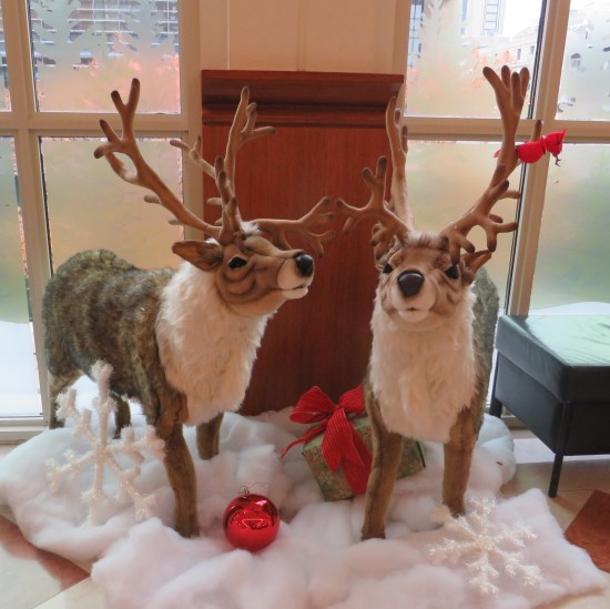 Two reindeer statues in a lobby, standing on a snow-shaped blanket.