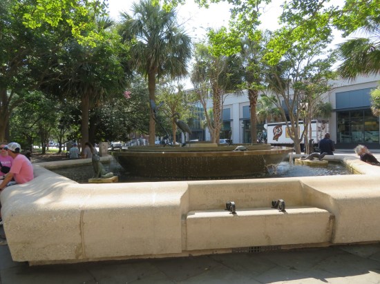 a barely running fountain surrounded by benches, numerous animal statues perched on it.