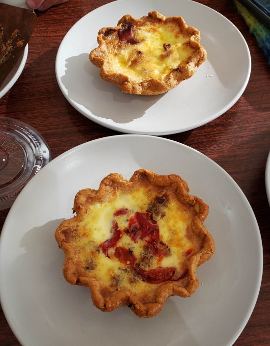 Two quiches plated on a wood table.