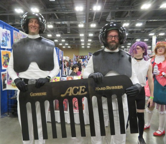 Two cosplayers as Dark Helmet's black-suited troops, carrying a giant comb between them.