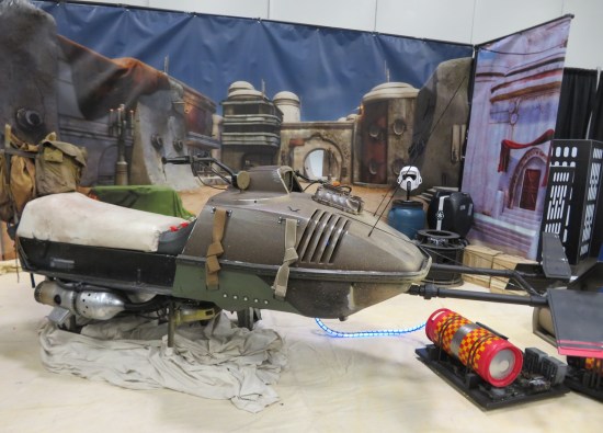 Fan-made Star Wars speeder bike displayed with alien world backdrop and accessories.