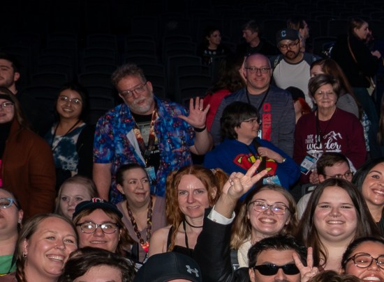 Distant shot of me waving awkwardly and Anne looking around her, away from the camera.