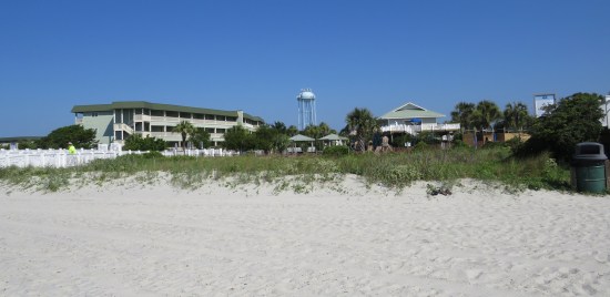 Buildings next to beach, beyond a plot of grass.