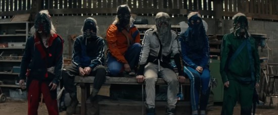 Six weirdos in blond wigs, droopy canvas masks and jumpsuits.