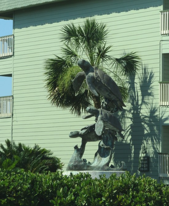 statue next to a nice hotel with three large sea turtles stacked on each other.