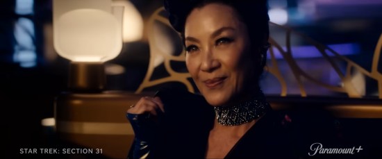 Michelle Yeoh in a black dress, smirking in a space nightclub.