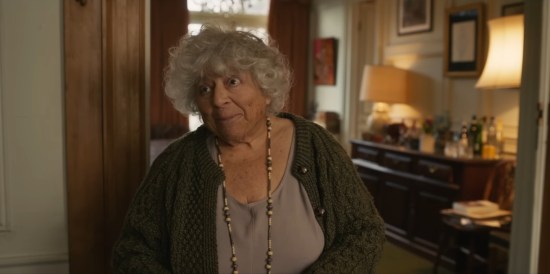 A kindly Miriam Margolyes in the doorway of a humble abode.