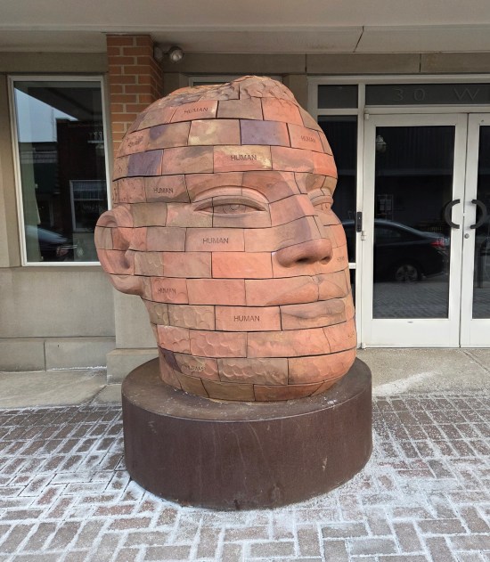 Sculpture of giant human head made entirely of bricks, some of which have the word "Human" engraved into them.
