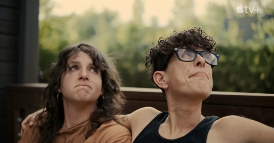 Happy couple sits on porch swing and looks upward together.