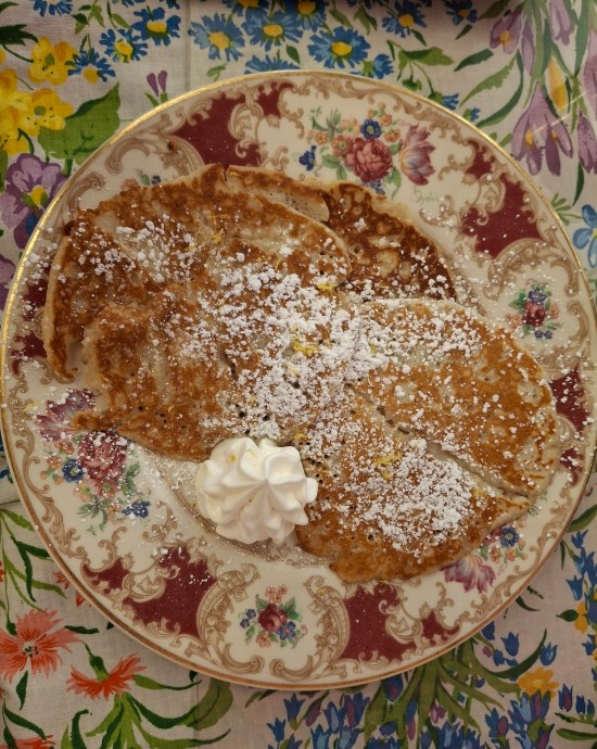 Overhead shot of lemon ricotta pancakes on flowery plate on even more flowery table.