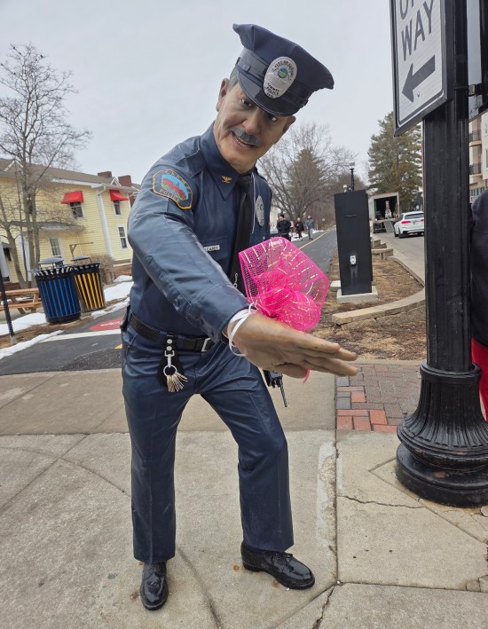 Statue of pointing beat cop. A real pink bow has been tied to its wrist.