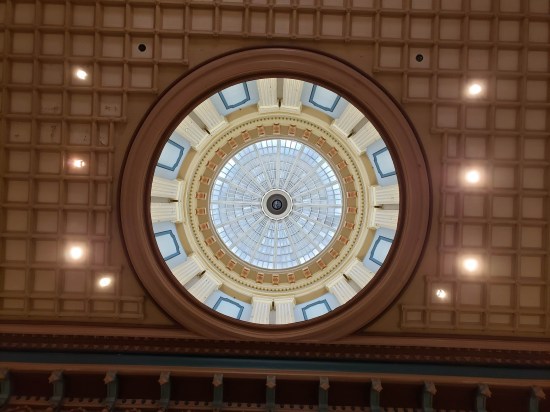 Looking upward toward the rotunda inside the capitol dome. Ceiling around it is brown lined tiles.