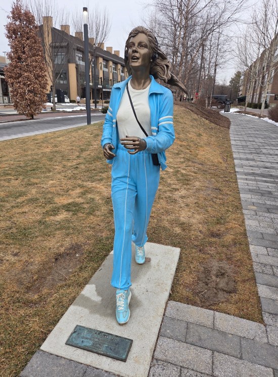 statue of woman jogging in blue tracksuit, wearing headphones and possibly a Walkman.