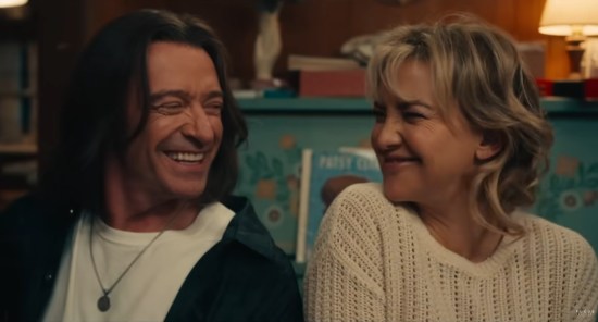 Hugh Jackman and Kate Hudson in character, smiling cutely at each other.