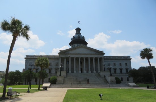 South Carolina State House with dome lawns, and palmettos at sidewalk corners.