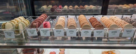Display case shelf with nine different varieties of macarons.