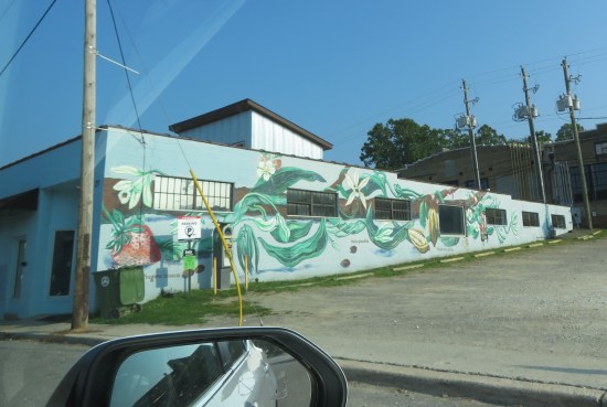 mural of big strawberry and vines snaking down the side of a white building.